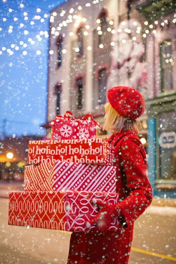 A woman carries several wrapped boxes outside in the snow