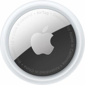 The image depicts an Apple - AirTag, a compact circular device with a white outer edge and a metallic center showcasing the Apple logo. The text along the perimeter includes "Ultra Wideband," "Bluetooth LE," "Designed by Apple in California," and "Assembled in China.