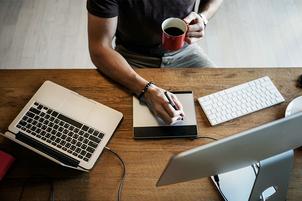 Person working at a desk with a laptop and a monitor