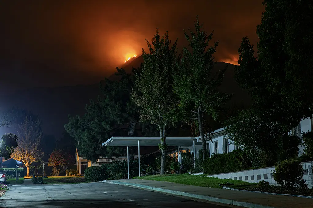 Wildfire burning behind jungle and mountains near a city