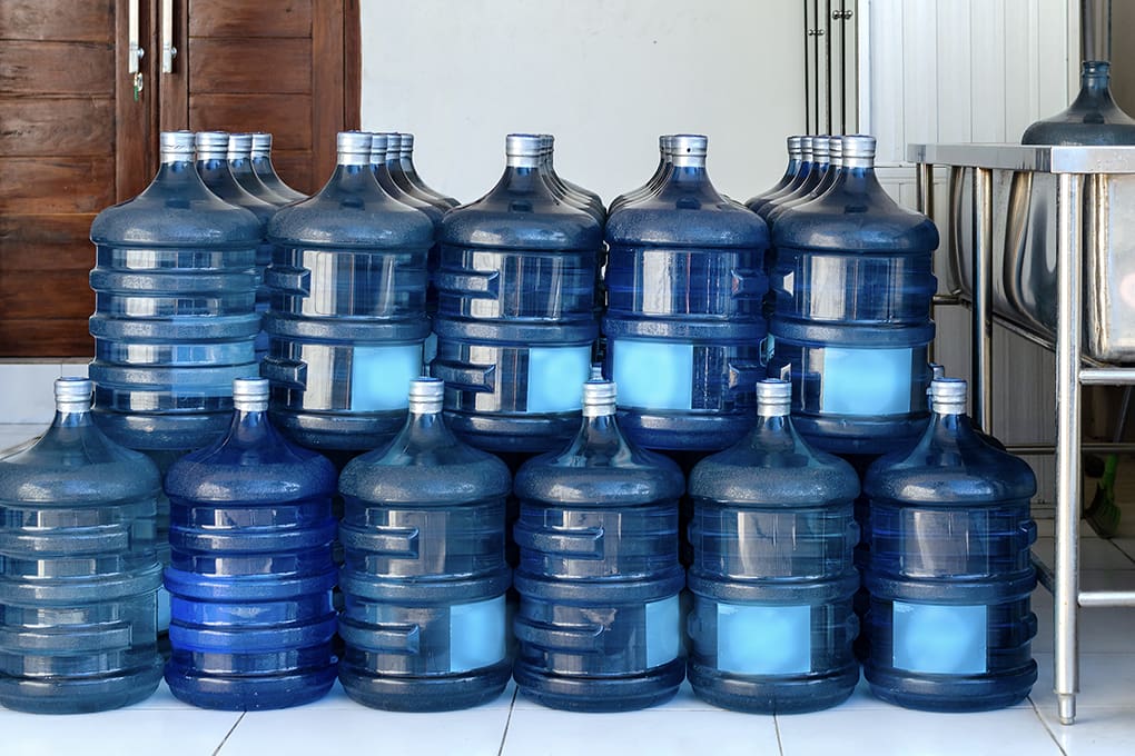 Stacks of large water containers against a wall. 