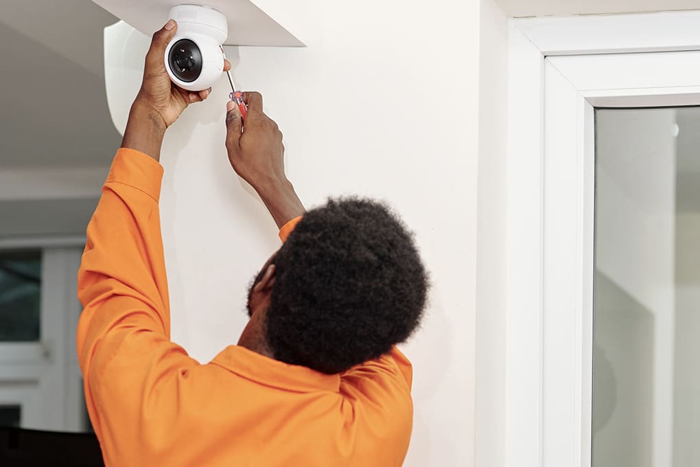 A man installing an indoor security camera system in a home. 